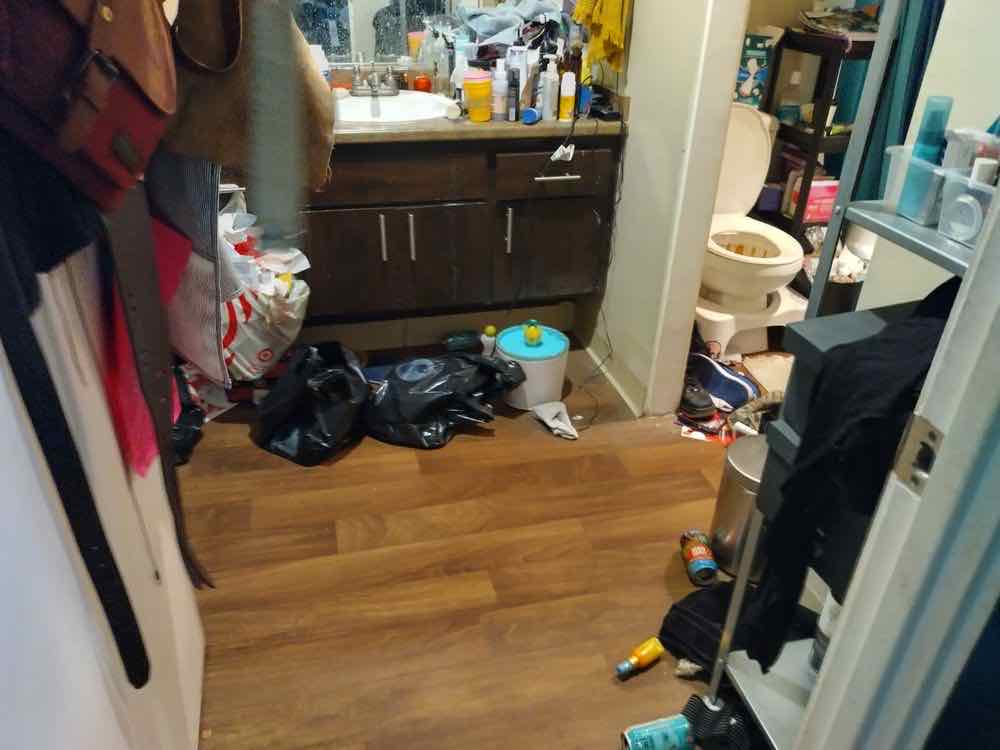 A cluttered bathroom with items across the floor before cleaning began