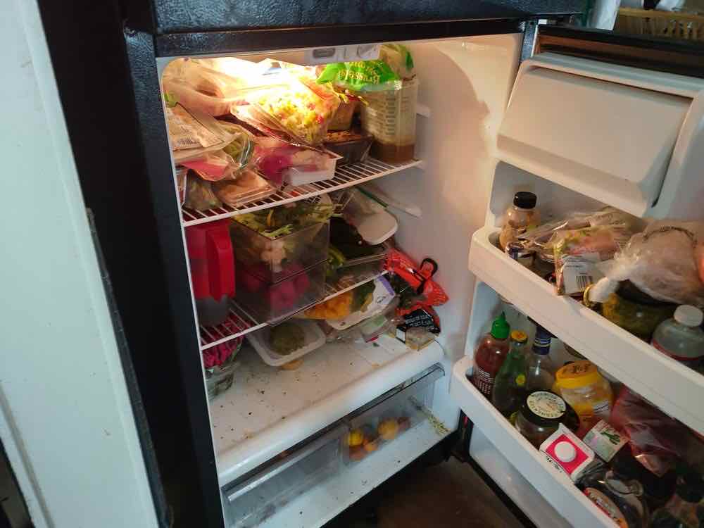 The inside of a refrigerator with spilled food on the shelves before a deep clean