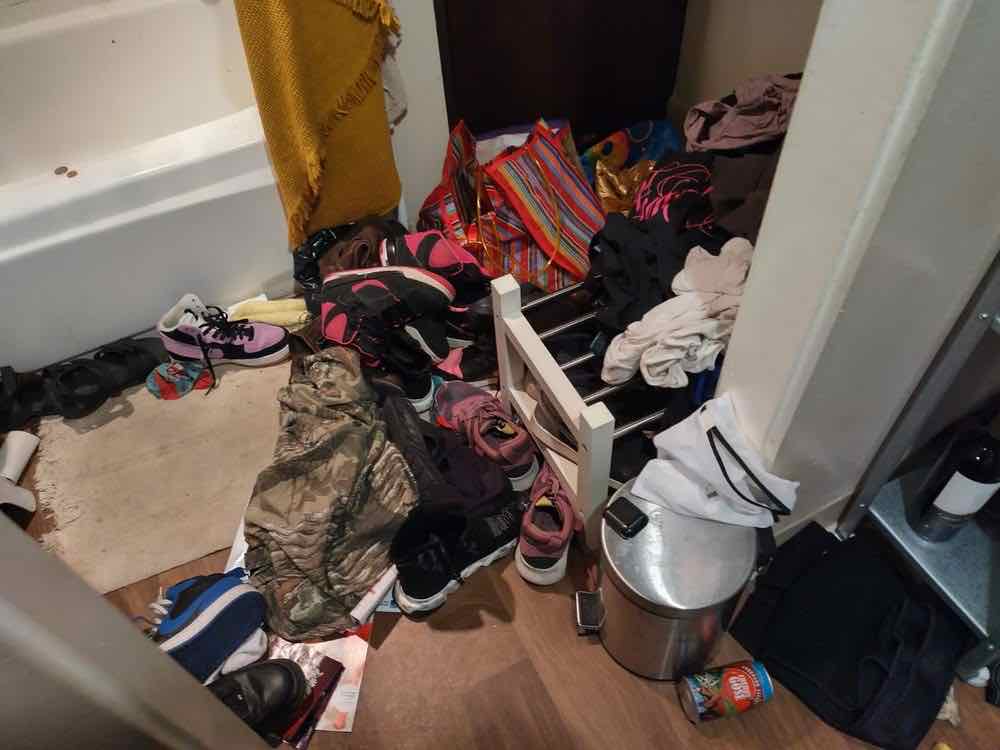 A hallway closet area covered in shoes and clothing before a move-out clean
